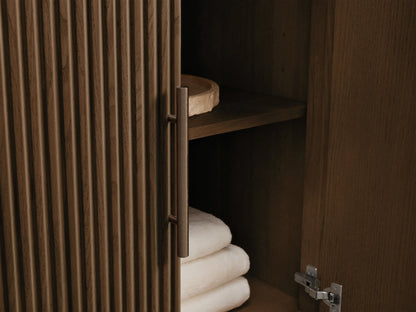 Finnley Single Vanity: white Carrara marble top, fluted dark wood, open drawer showing towels & bottles. Antique bronze pull.