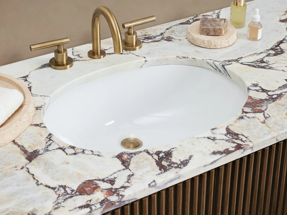 Finnley Wide Single Vanity, dark brown fluted wood, white marble top with oval sink & gold faucet, gold hardware.