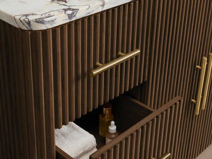 Finnley Wide Single Vanity's open fluted dark brown oak cabinet door with long brass handle, revealing interior with white towels.