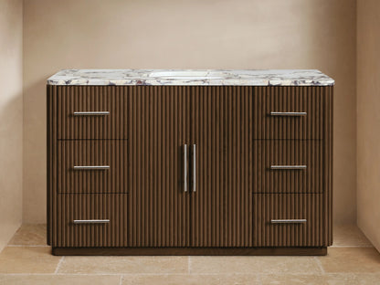 Finnley Wide Single Vanity: dark brown ribbed oak wood, white Carrara marble top, chrome faucet, six drawers, two doors.