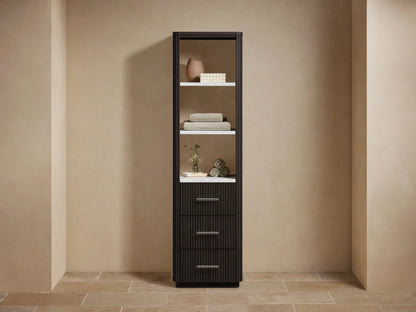 Tall dark brown Finnley bath cabinet with open shelves displaying decor/towels & three fluted drawers with silver pulls, against a beige wall.