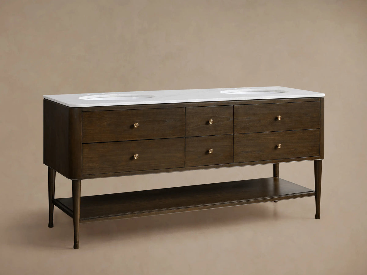 Laurent Double Vanity. Dark Bahasa Brown wood vanity with white Carrara marble top & oval sink. Top drop-down drawer open, brass knobs.
