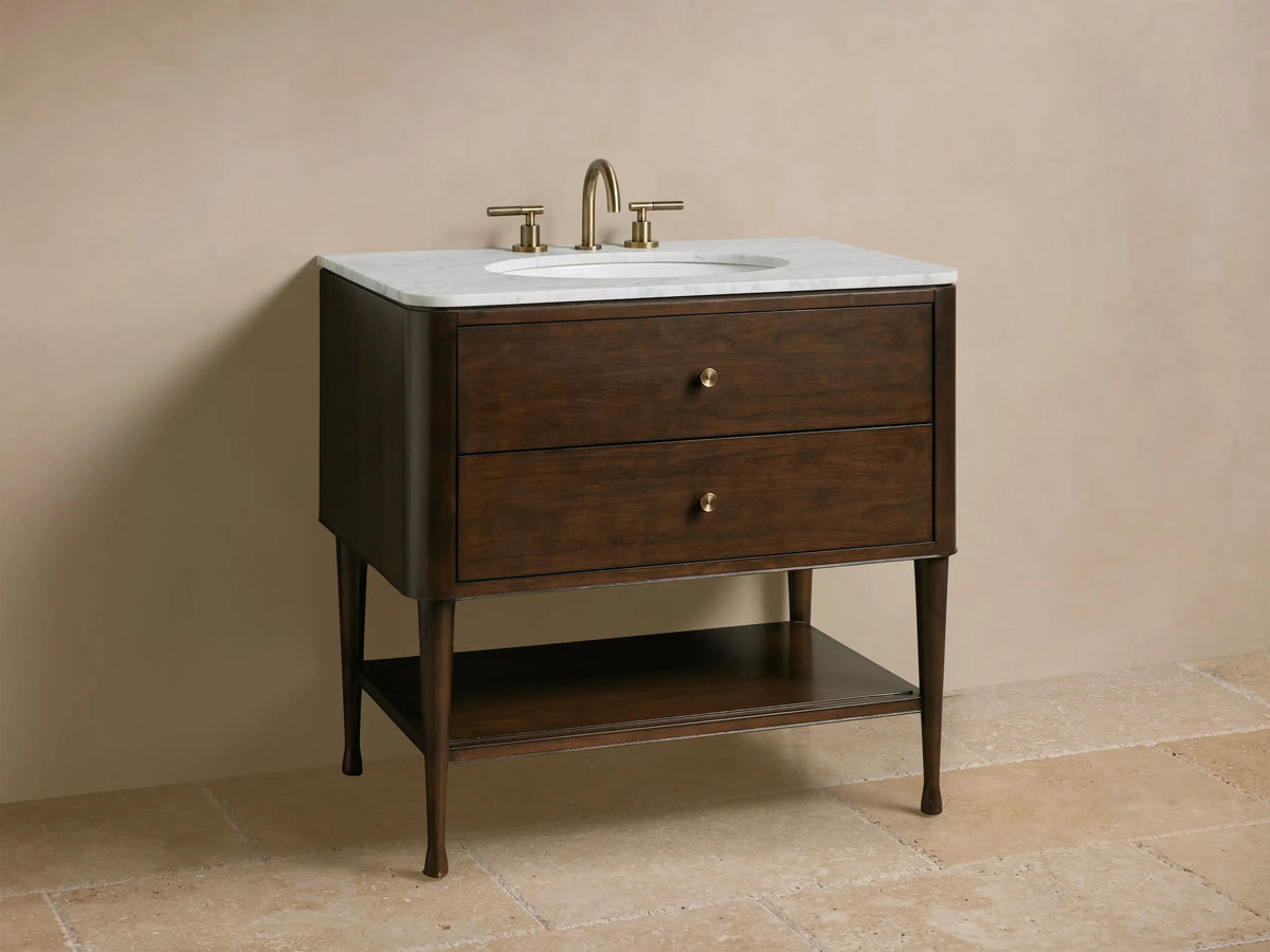 Close-up of Laurent Single Vanity: dark brown wood with white marble top, partially open drop-down drawer revealing organizer. Polished knobs.