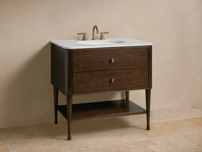 Close-up of Laurent Single Vanity: dark brown wood with white marble top, partially open drop-down drawer revealing organizer. Polished knobs.