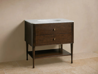 Laurent Single Vanity: dark wood frame, white marble top with oval sink & gold faucet, two drawers, lower open shelf.