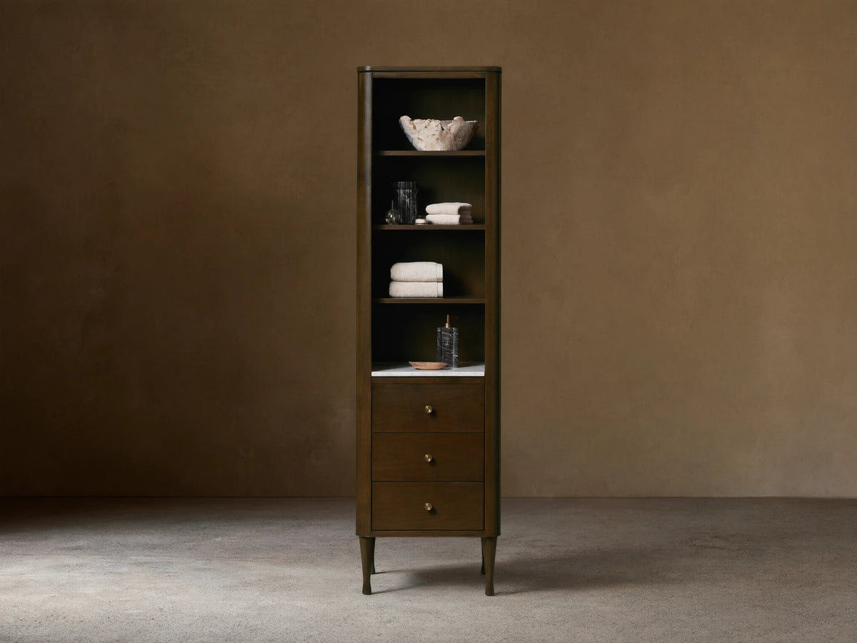 Tall Laurent Bath Cabinet, dark wood, white marble, 4 shelves with towels & decor, 3 drawers, brass pulls.