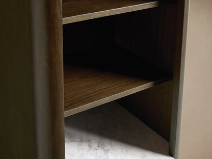 Laurent Tall Bath Cabinet close-up. Dark brown wood, white marble top with perfume bottle & bowl. Open drawer with folded towels, brass knob.