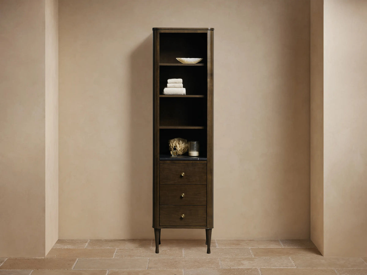 Tall Laurent Bath Cabinet in Bahasa Brown, with open shelves, black stone top, and three drawers with brass knobs.