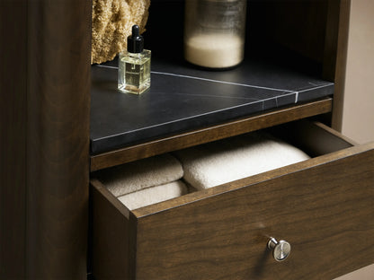 Laurent Tall Bath Cabinet: narrow, dark brown, with open shelves, a dark stone top, and three drawers with light pulls.