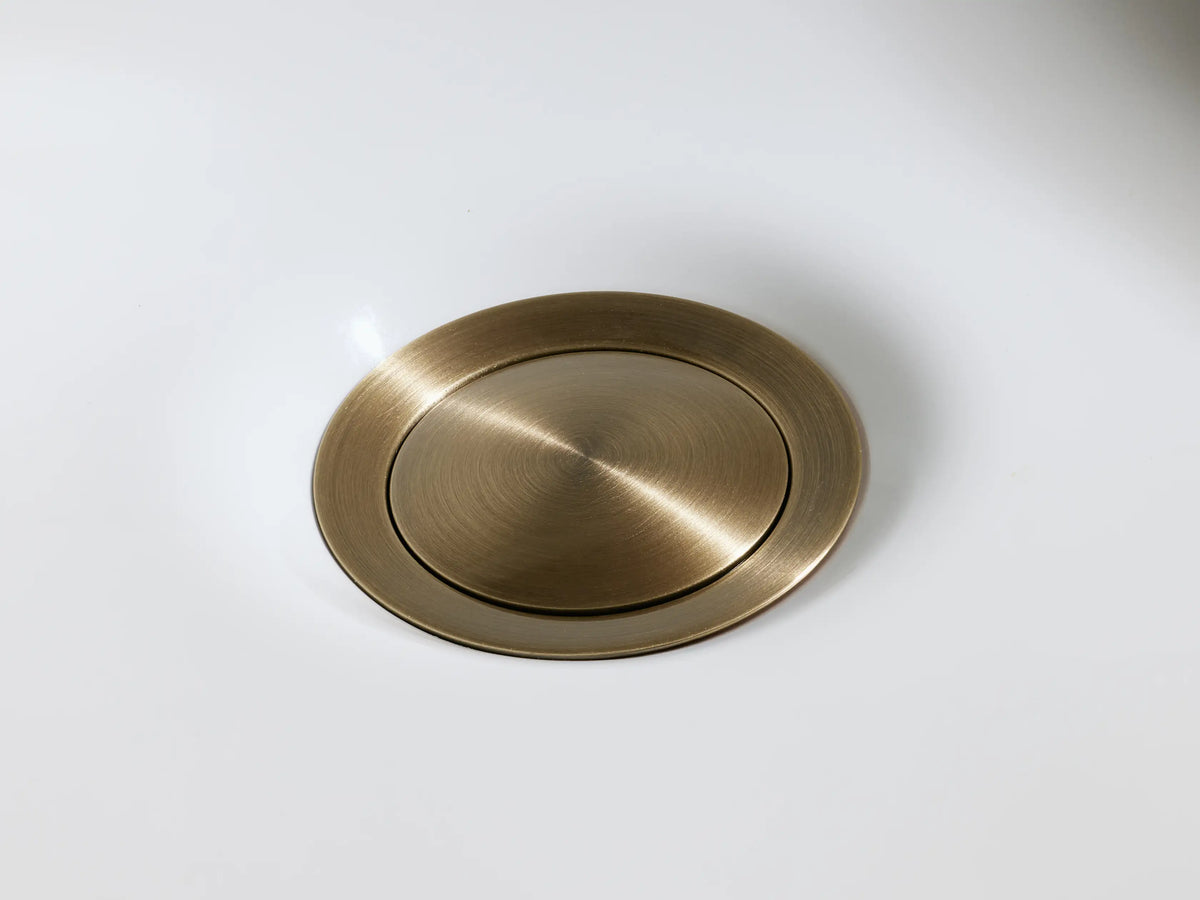 Lomas Faucet in antique brass finish, featuring a cross-styled handle on a round base, displayed on a marble surface.