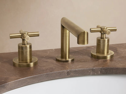Lomas Faucet in antique brass finish, featuring a cylindrical spout and two cross-styled handles on a dark countertop.