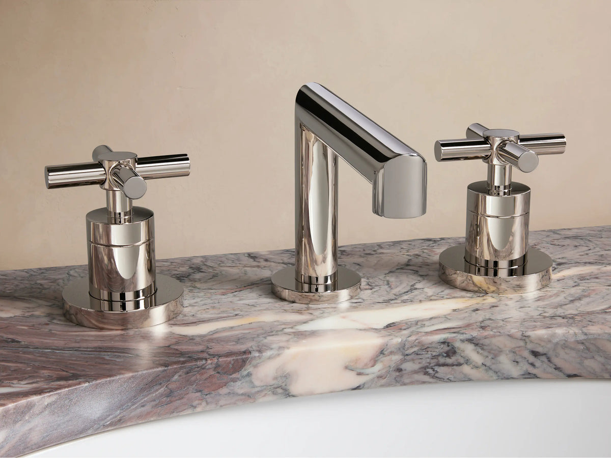 Sleek chrome bathroom faucet set with a contemporary design, featuring two cross-handle knobs and a central spout on a marble counter.