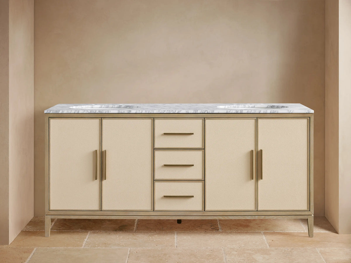 Malone Double Vanity in Bone finish. Light wood frame, cream shagreen cabinet doors & drawers with brass handles. White marble top.