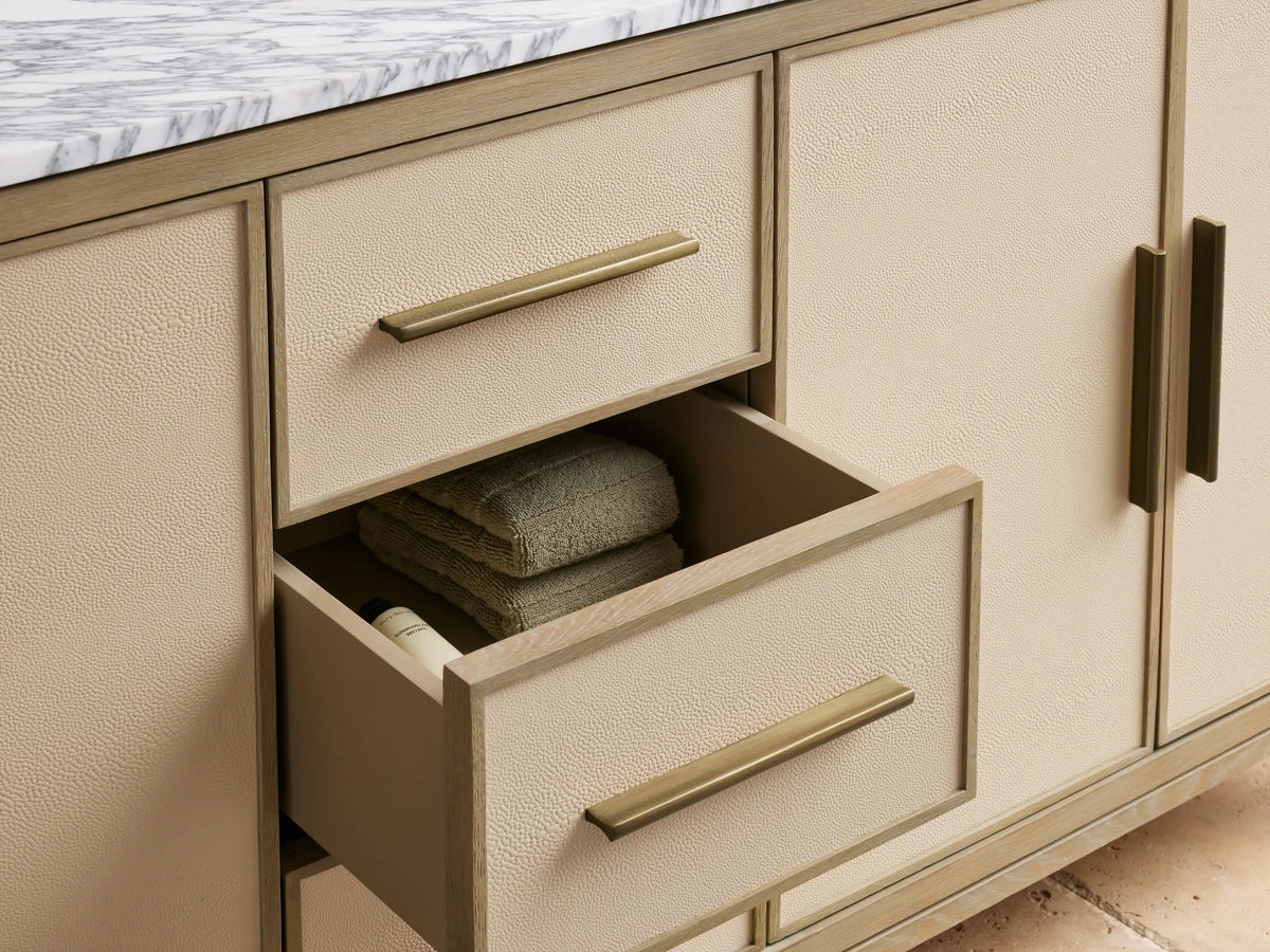 Malone Double Vanity: light oak, marble top. Textured cream drawers and open cabinet with bronze pulls, folded towels.