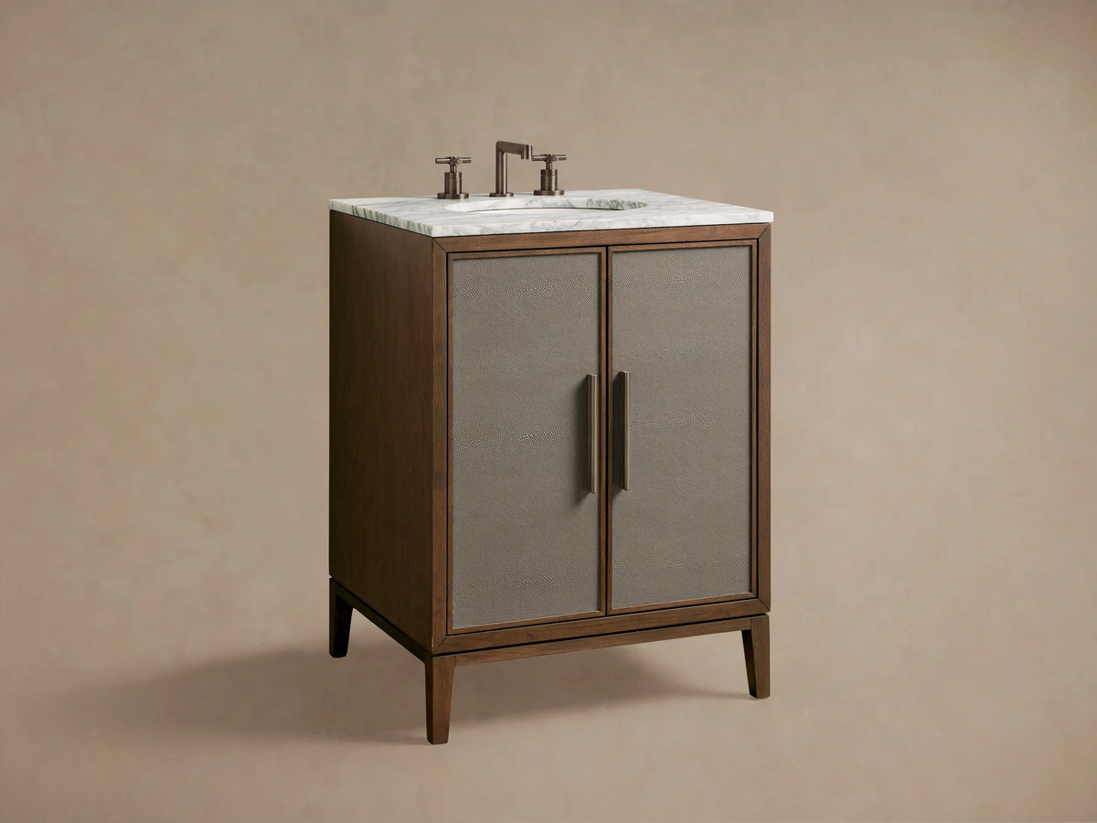 Close-up of Malone Powder Vanity with open walnut cabinet. Beige shagreen door, polished nickel handle. Shelves hold a marble jar, bottle, and sage towels.