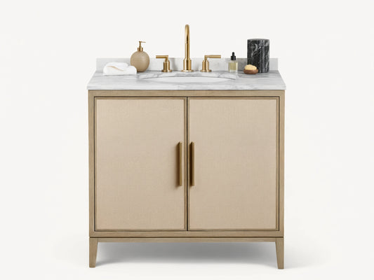 Malone Single Vanity with light wood frame, beige shagreen doors, white marble top, and brass hardware, in a bathroom setting.