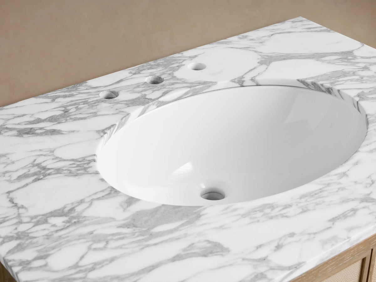 Malone Single Vanity close-up: white oval sink set in a veined marble top with antique brass faucet and gold accessories.