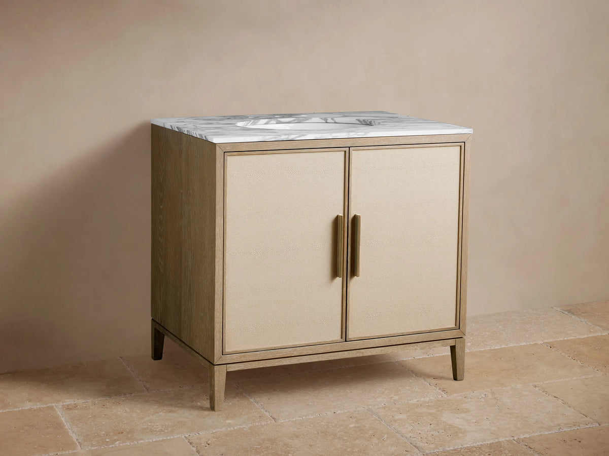 Malone Single Vanity in bone finish oak, white marble top with sink & brass faucet, shagreen-textured doors with brass handles.