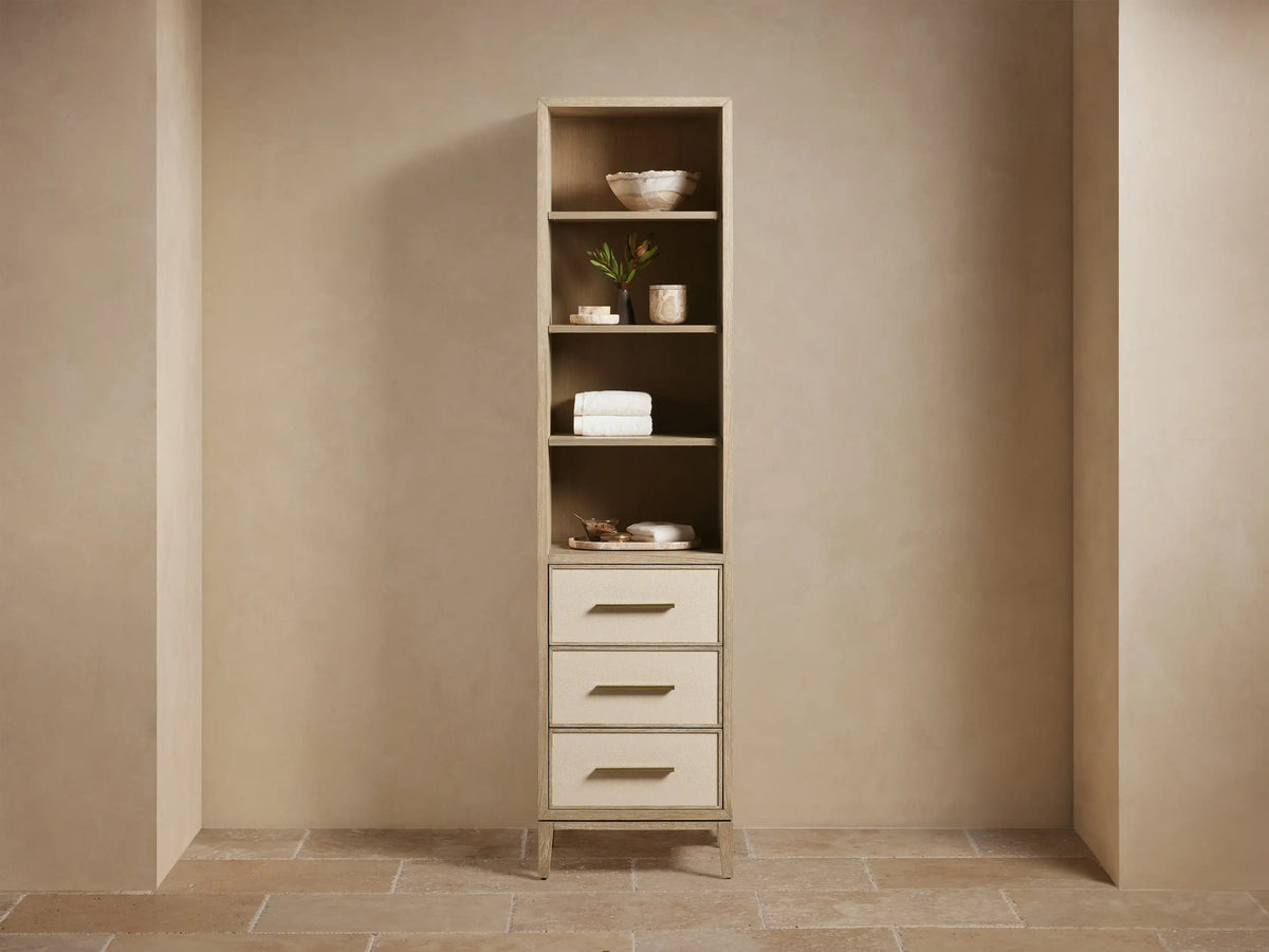 Tall Malone Bath Cabinet, bone finish oak. Open shelves hold towels & decor; 3 drawers have light faux shagreen fronts.