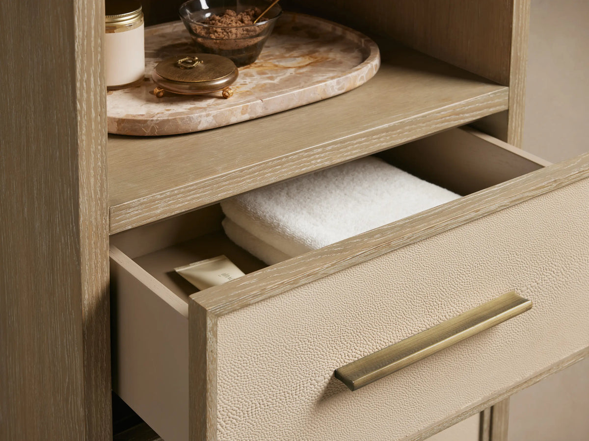 Malone Tall Bath Cabinet in bone finish oak, with 3 open shelves & 3 drawers featuring light shagreen fronts & brass pulls.