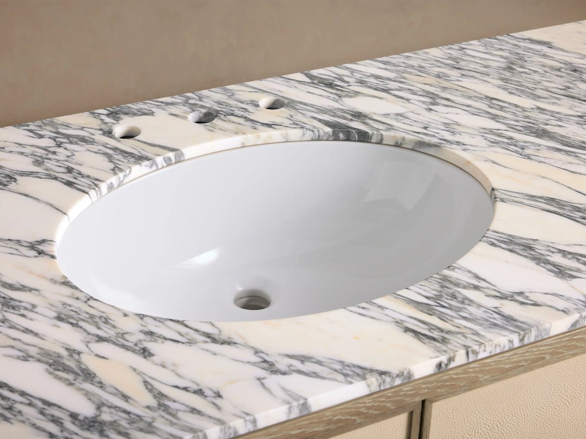 Malone Wide Single Vanity: White oval sink in veined Arabescato marble countertop, widespread brass faucet with cross handles.