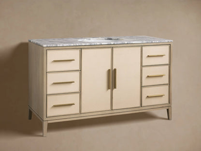 Malone Wide Single Vanity in bone finish oak with a white marble top, brass faucet, sink, and light beige shagreen doors/drawers.