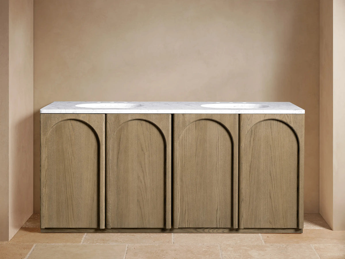 Provo Double Vanity in oak wood features four arched cabinet doors, a white stone top with dual ceramic sinks, and brass faucets.