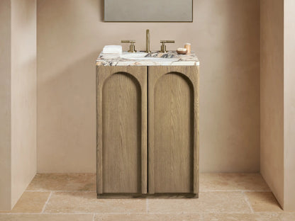 Provo Powder Vanity with oak wood finish, honed marble top, brass faucet, oval undermount sink, two arched doors, set against a neutral-toned bathroom.