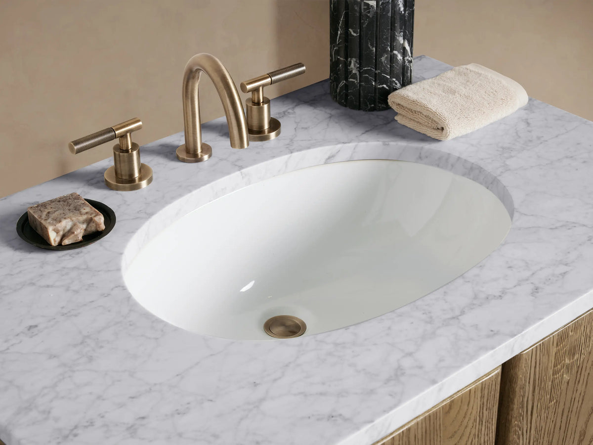 Light oak Provo Single Vanity with two arched doors, white marble top, oval sink, against a pale wall & tiled floor.