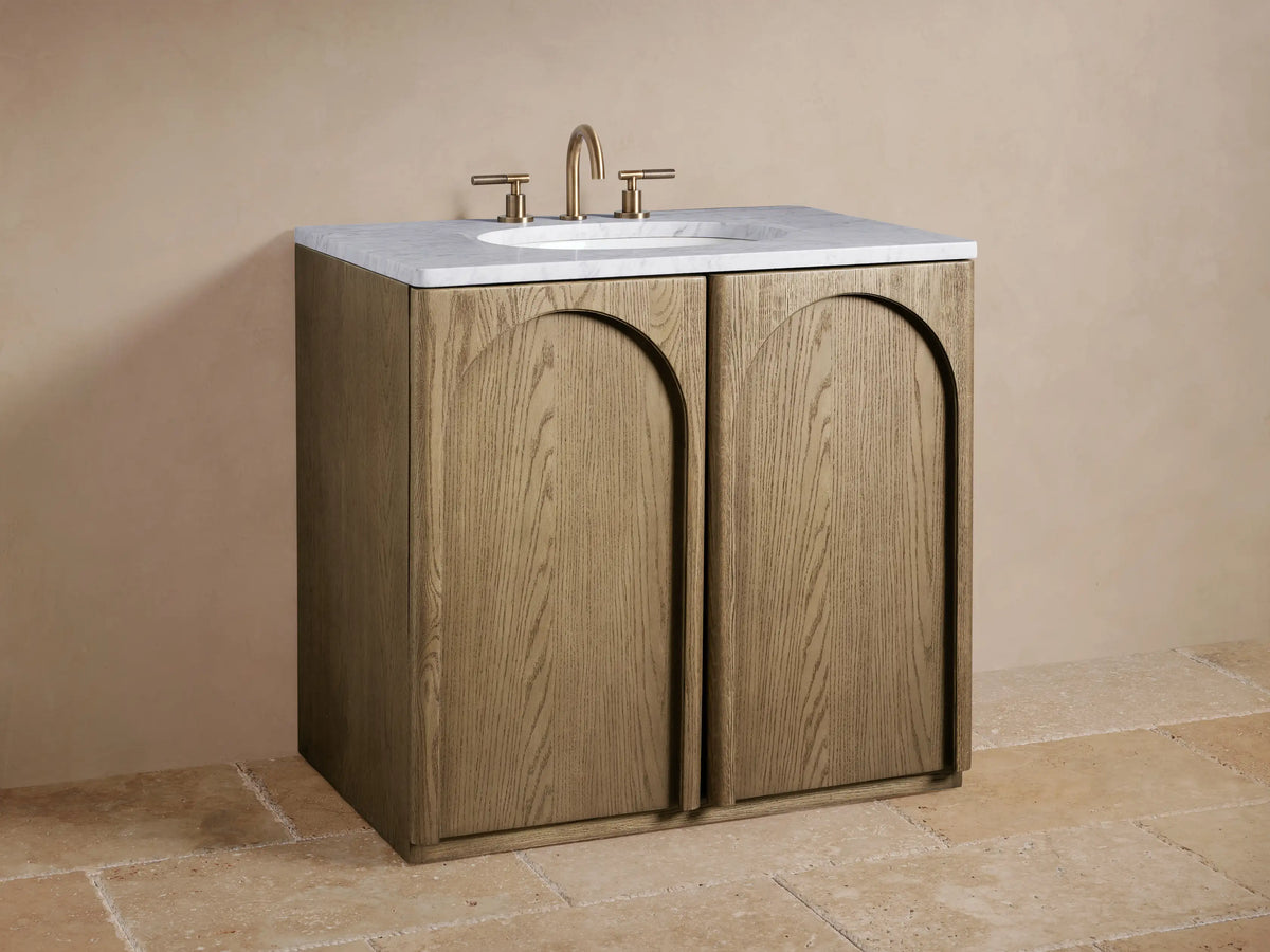 Open Provo Single Vanity cabinet, light oak door, dark wood interior. Folded beige towels, black marble box, and perfume bottle on shelves.