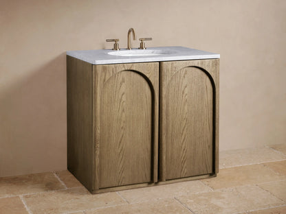 Open Provo Single Vanity cabinet, light oak door, dark wood interior. Folded beige towels, black marble box, and perfume bottle on shelves.