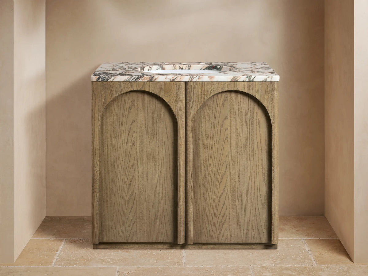 Provo Single Vanity with oak wood base, arched doors, marble stone top, twin brass faucets, and ceramic sink.