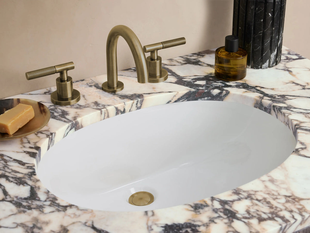 Oak wood Provo Single Vanity with a marble stone top. Features two arched cabinet doors and stands on a tiled floor.