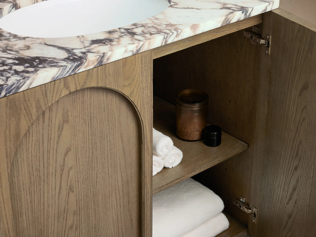 Oval ceramic undermount sink on marble countertop with gold faucet on Provo Single Vanity. Cream and dark marbling.