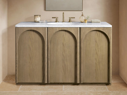 Provo Single Wide Vanity with oak wood doors and stone top, featuring an oval sink and brass faucets, in a neutral-toned bathroom.