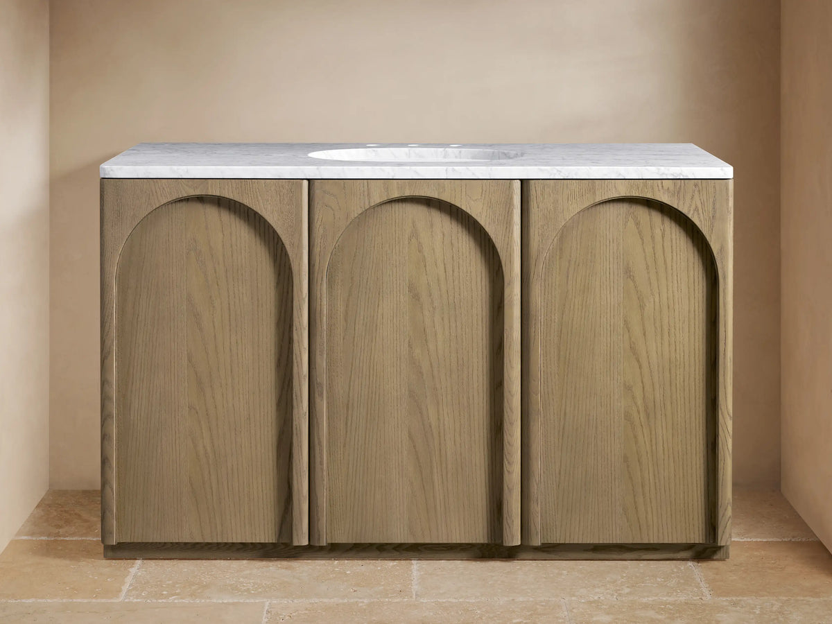 Provo Single Wide Vanity with oak wood doors and stone top, featuring an oval sink and brass faucets, in a neutral-toned bathroom.