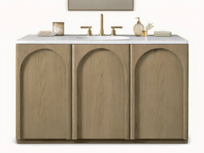 Provo Single Wide Vanity with oak wood doors and stone top, featuring an oval sink and brass faucets, in a neutral-toned bathroom.