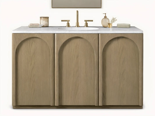 Provo Single Wide Vanity with oak wood doors and stone top, featuring an oval sink and brass faucets, in a neutral-toned bathroom.