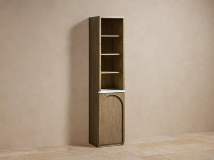 Tall oak wood etagere with a marble stone top, featuring open shelves with decor items and a closed arched door at the bottom.