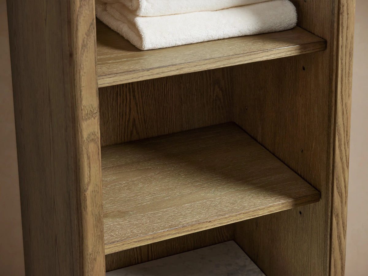 Oak wood Provo Etagere with white marble stone top, holding toiletries and folded towels on lower shelf, close-up view.