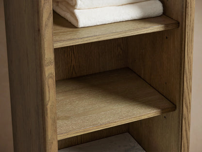 Oak wood Provo Etagere with white marble stone top, holding toiletries and folded towels on lower shelf, close-up view.