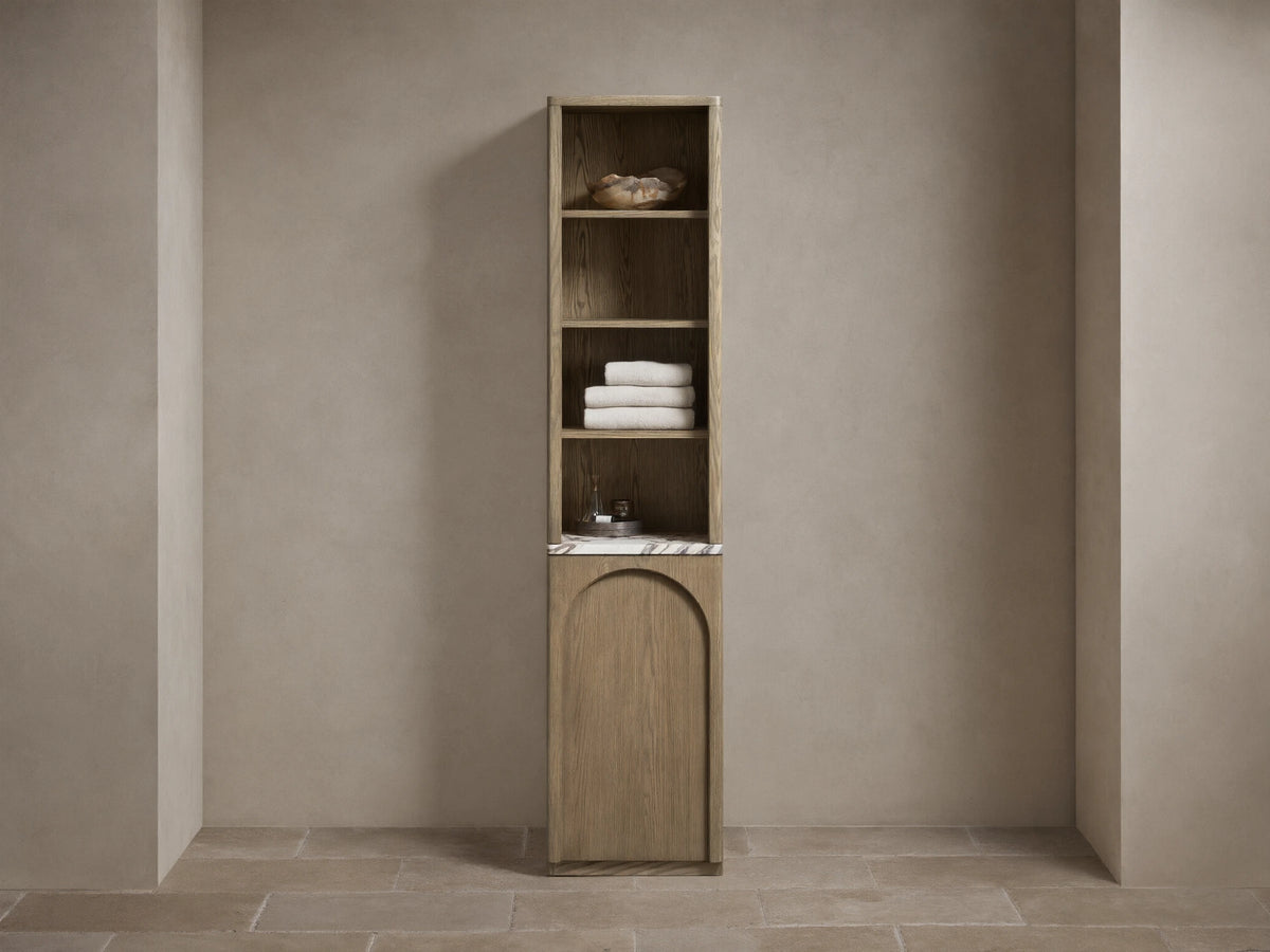 Tall, narrow Provo Etagere with oak wood frame, featuring shelves with towels and items. Marble stone top and closed cabinet below.