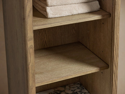 The Provo Etagere features a marble stone top with distinct veining on a wooden shelf, holding two folded towels and decorative items.