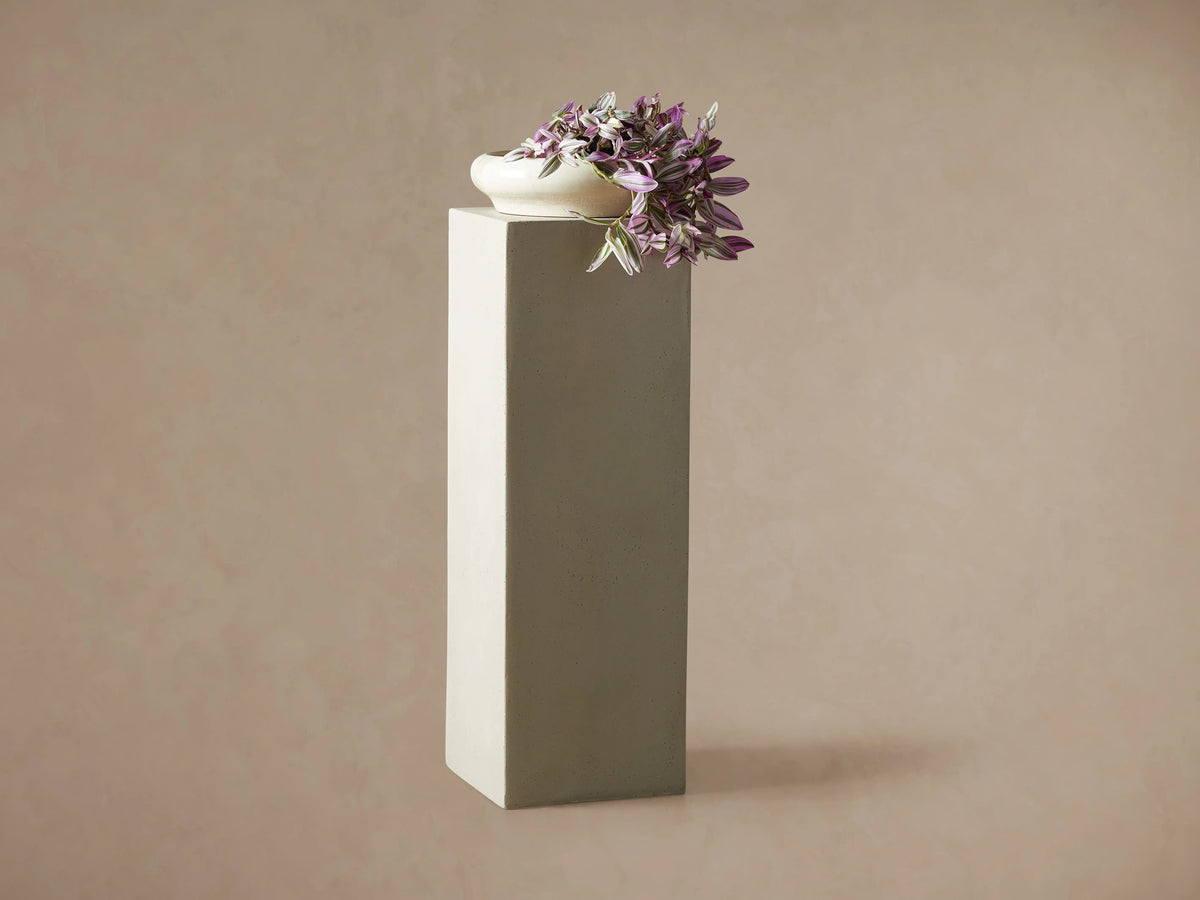 Light gray rectangular fiberglass Outdoor Pedestal standing on a dark wood floor against a beige wall.