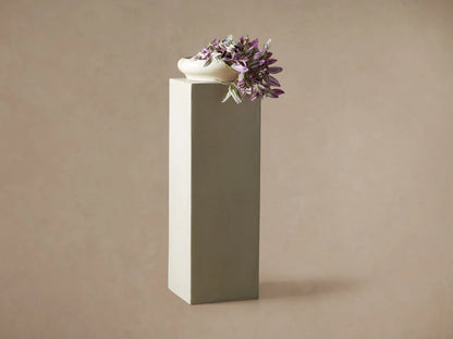 Light gray rectangular fiberglass Outdoor Pedestal standing on a dark wood floor against a beige wall.