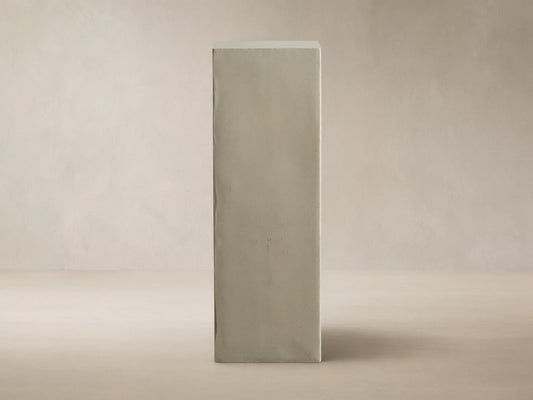 Light gray rectangular fiberglass Outdoor Pedestal standing on a dark wood floor against a beige wall.