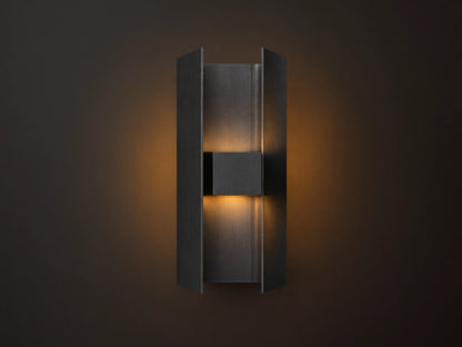 Sidney Outdoor Sconce, a graphite aluminum fixture casting warm LED light up and down against a taupe wall.