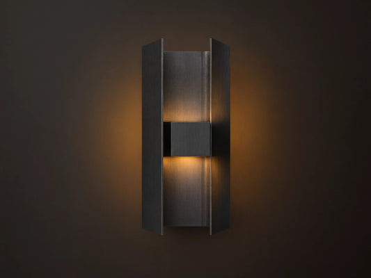 Sidney Outdoor Sconce, a graphite aluminum fixture casting warm LED light up and down against a taupe wall.