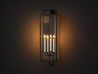 Hendricks Outdoor Sconce: black iron frame with clear glass panels, four lit candle-style bulbs, mounted vertically on a taupe wall.
