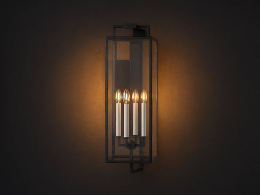 Hendricks Outdoor Sconce: black iron frame with clear glass panels, four lit candle-style bulbs, mounted vertically on a taupe wall.